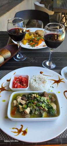 una mesa con platos de comida y dos copas de vino en MAISON CARREE, en Andilana