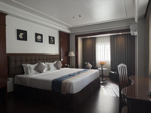 a hotel room with a large bed and a desk at Madison Crown Hotel in Angeles