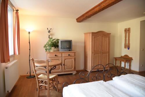 a bedroom with a bed and a table and a tv at Altstadthotel Garni Schlundhaus & Rautenkranz in Meiningen