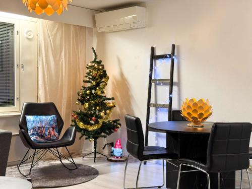 a christmas tree in a living room with a table and chairs at Aurora Home Rovaniemi in Rovaniemi
