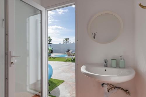 un bagno bianco con lavandino e specchio di The Suite Villa a Playa Blanca