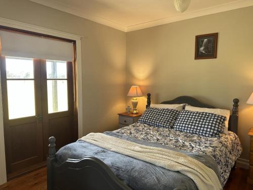 Loudawn Homestead في كورا: غرفة نوم بها سرير مع وسائد ونافذة