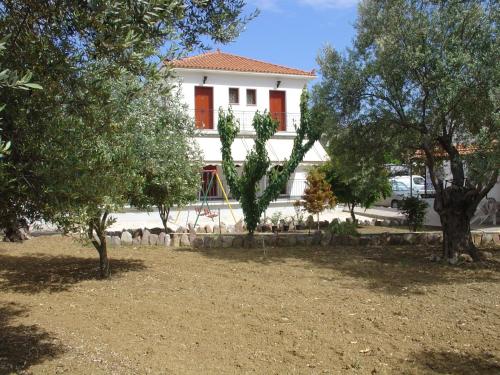 Loutrópolis ThermísにあるApartments Villa Myrtoの目の前に木々が植えられた白い家