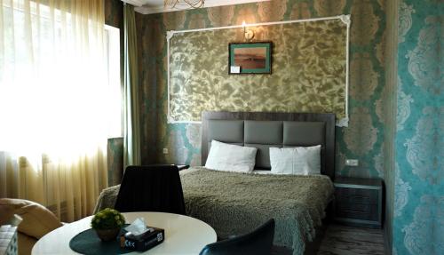 Un dormitorio con una cama y una mesa y sillas. en Чичхани Chichxani Kambuz, en Aghk'ilisa