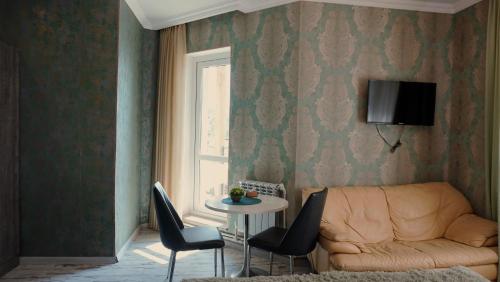 Una sala de estar con un sofá y una mesa con sillas. en Чичхани Chichxani Kambuz, en Aghk'ilisa