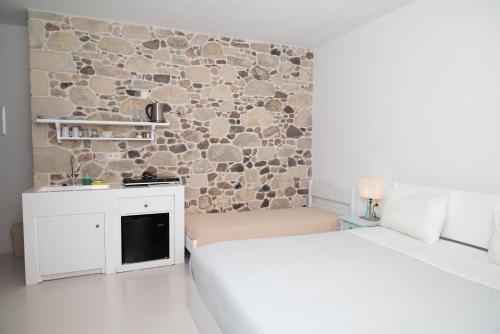 Un dormitorio con dos camas y una pared de piedra. en Elia, en Kavoúsion