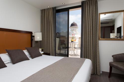 um quarto de hotel com uma cama e uma grande janela em Hotel Balmoral em Barcelona