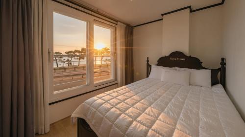ヤンヤンにあるYangyang Verit Pensionのベッドと大きな窓のある寝室