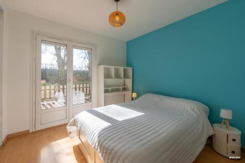 ein blaues Schlafzimmer mit einem Bett und einem Fenster in der Unterkunft La maison du bonheur in Pin-Balma