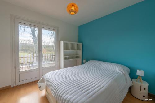 ein blaues Schlafzimmer mit einem Bett und einem Fenster in der Unterkunft La maison du bonheur in Pin-Balma