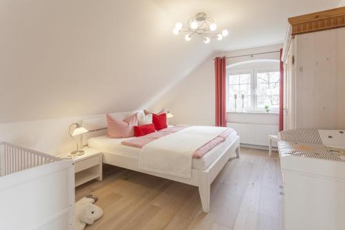 a white bedroom with a bed and a window at Haus Eichenwald in Glowe