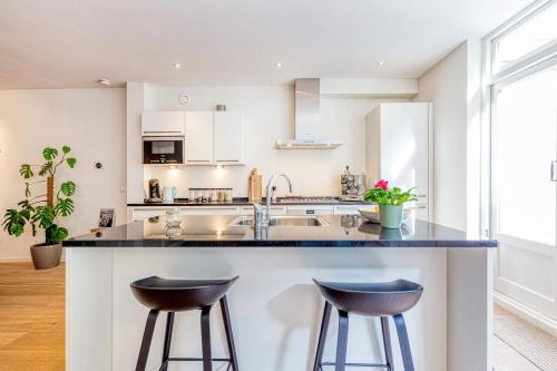 a kitchen with a sink and two bar stools at TOP location 2 bedroom groundfloor home with garden in The Hague