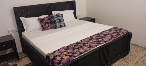 a large bed with a black frame and white sheets and pillows at TheChef NungwiBungalow in Kidoti