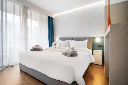 a bedroom with a large white bed with towels on it at Premier Pool View Studio 348 KoraResort in Layan Beach