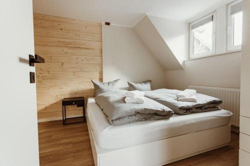 a bedroom with a white bed with a wooden wall at Harzchalet Brockenbahn 2A in Elend