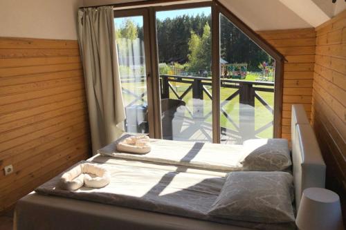 a bedroom with two beds and a large window at Vērbeļnieki in Pērkone