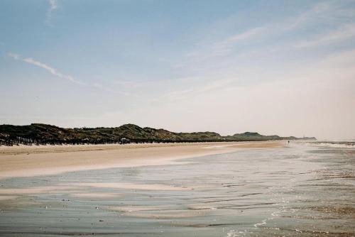 ein Strand mit ein paar Leuten, die auf dem Sand laufen in der Unterkunft Hus an de Waterkant in Juist