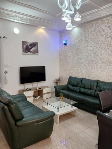 sala de estar con sofás verdes y TV de pantalla plana en MAG GUEST house, en Abomey-Calavi