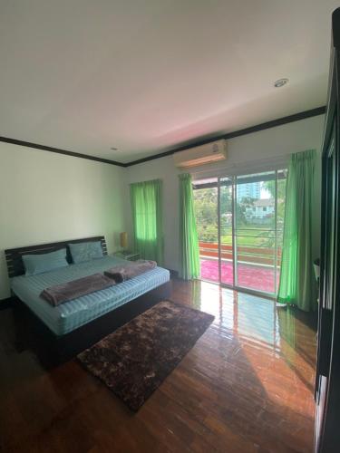 ein Schlafzimmer mit einem Bett mit grünen Vorhängen und Holzböden in der Unterkunft Baan Rungrojn HuaHin in Hua Hin