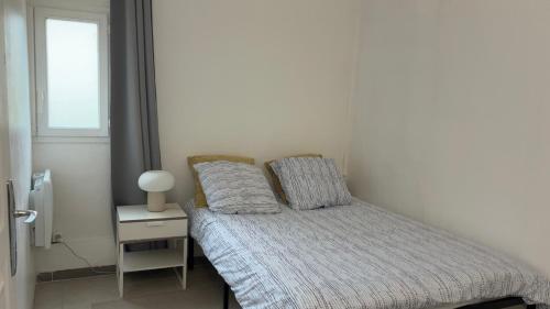 a bedroom with a bed with a nightstand and a window at Le Nid Chaleureux Ecoresponsable in Sevran