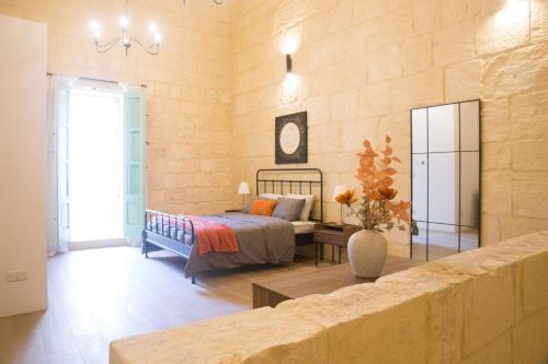 Un dormitorio con una cama y una mesa en una habitación. en Vittoria - charming 500-year-old house nestled within the fortified walls of Birgu, en Birgu