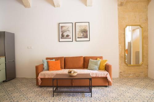 una sala de estar con un sofá y una mesa en Vittoria - charming 500-year-old house nestled within the fortified walls of Birgu, en Birgu