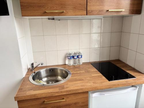 a kitchen counter with a sink and bottles of water at Super appartement in Malesherbes