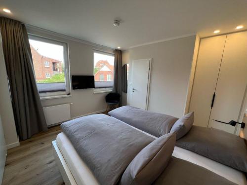 于斯德Dünen Lodge 4的一间带一张大床和两扇窗户的卧室