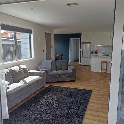 ein Wohnzimmer mit 2 Sofas und einer Küche in der Unterkunft Modern & Comfort in Central Alexandra in Alexandra