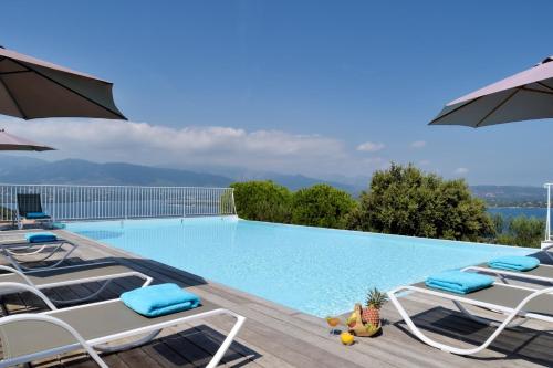 une grande piscine avec chaises et parasols dans l'établissement Mini villa Marina Serena, à Porto-Vecchio
