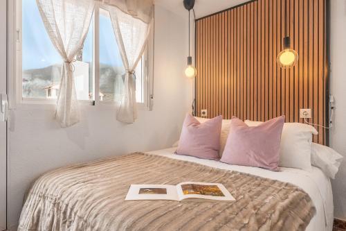Un dormitorio con una cama con un libro encima. en Estudio Sierra Nevada, en Güéjar-Sierra