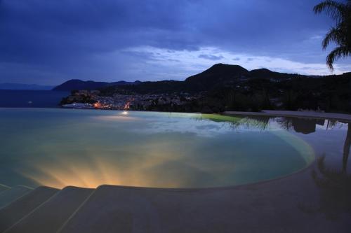a swimming pool with a view of the ocean at night at Hotel Villa Enrica - Aeolian Charme in Lipari
