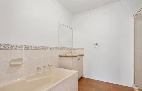 a white bathroom with a tub and a sink at Perfect peaceful stay in Melton