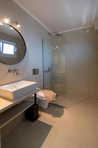 a bathroom with a shower and a sink and a mirror at Hotel Elina in Perdika
