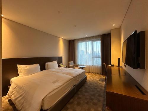 a hotel room with a bed and a flat screen tv at LOTTE CITY HOTEL Ulsan in Ulsan
