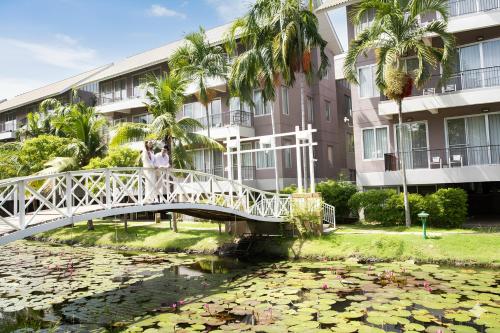 a man standing on a bridge over a pond with water lilies at The Leela Resort & Spa Pattaya in Pattaya