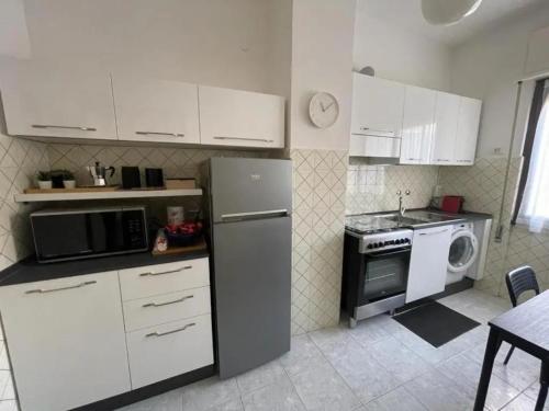 een keuken met witte kasten, een koelkast en een magnetron bij Sweet 16 in Rapallo