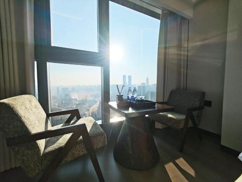 Zimmer mit einem Tisch, 2 Stühlen und einem großen Fenster in der Unterkunft Su Lu Hotel in Guiyang
