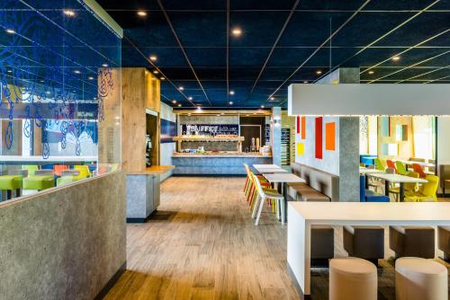 un restaurant avec des plafonds bleus, des tables et des chaises dans l'établissement ibis budget Saint Quentin Yvelines - Vélodrome, à Montigny-le-Bretonneux