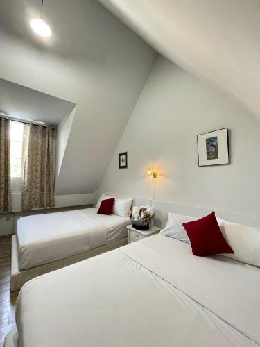 two beds in a room with white walls and red pillows at Chermonné House เฌอมอญ in Ban Komo Chet
