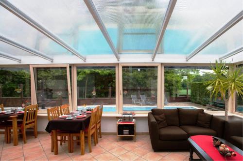 a conservatory with a couch and tables and chairs at B&B Woodside in Torhout