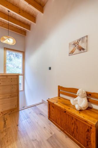 a teddy bear sitting on a wooden bench in a room at Chalet cosy et neuf, Grande Terrasse, Vue panoramique in Saint-Jean-de-Sixt