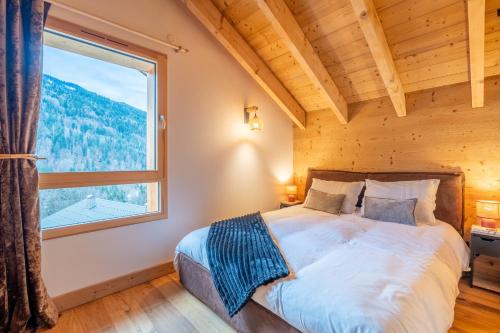 a bedroom with a bed and a large window at Chalet cosy et neuf, Grande Terrasse, Vue panoramique in Saint-Jean-de-Sixt