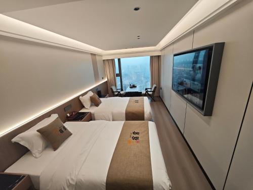 ein Hotelzimmer mit zwei Betten und einem Flachbildfernseher in der Unterkunft Su Lu Hotel in Guiyang