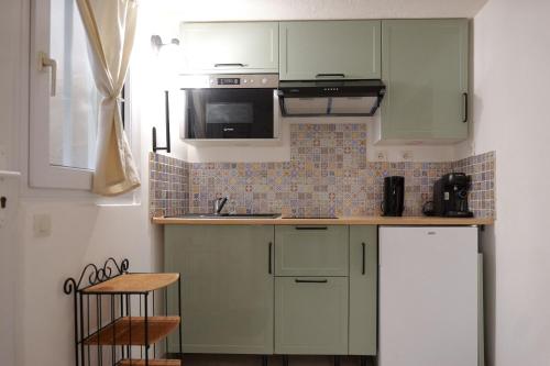 Elle comprend une petite cuisine avec des placards verts et un évier. dans l'établissement studio 2 personnes rue travot, à Les Sables-dʼOlonne