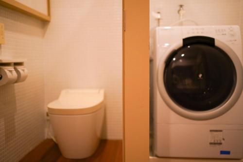 Un baño con lavadora al lado de un inodoro. en 結びの小宿 縁 by Wellbe, en Kobe