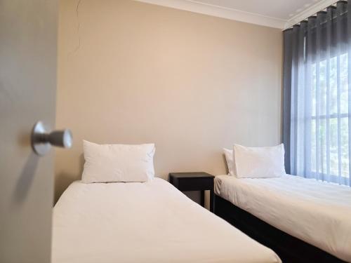 two beds in a room with a window at El Toro Motel in Warwick Farm