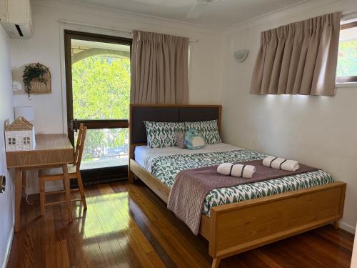 een slaapkamer met een bed, een bureau en een raam bij 4BR big family house with huge pool in Brisbane