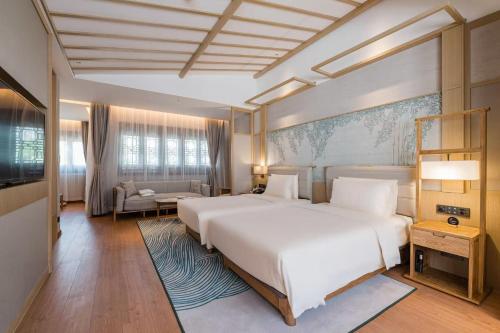 a bedroom with a large white bed and a couch at Atour S Hotel SHanghai Baoshan Gucun Park in Shanghai