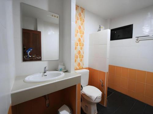 a bathroom with a sink and a toilet and a mirror at Phakawan Hotel in Ban Nong Chik